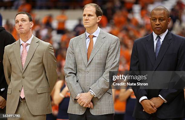 Assistant coaches Gerry McNamara, Mike Hopkins and Adrian Autry of the Syracuse Orange look on as they stand on the court during the National Anthem...