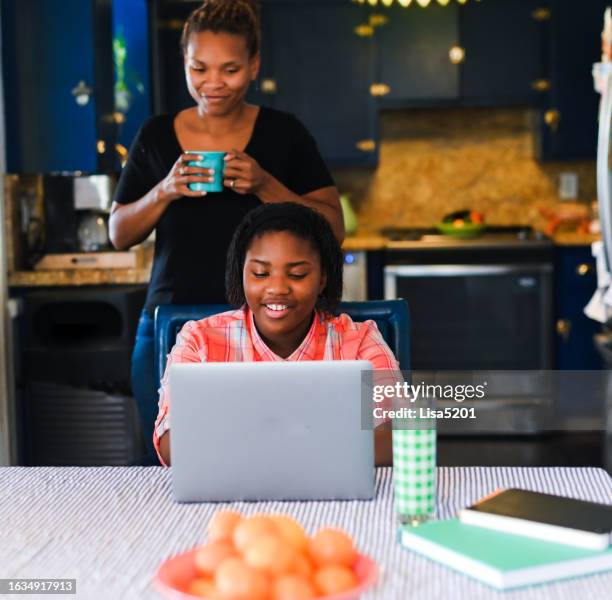 adolescente usa computadora portátil en casa en la cocina familiar con mamá entrometida mirando por encima del hombro - entrometido fotografías e imágenes de stock
