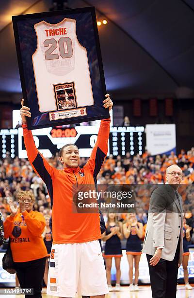 Brandon Triche of the Syracuse Orange smiles as he holds up his framed jersey during senior night as head coach Jim Boeheim looks on prior to the...