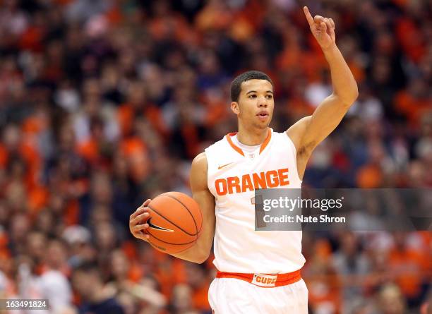 Michael Carter-Williams of the Syracuse Orange signals to teamates, holding up a number one sign as he takes the ball down the court during the game...