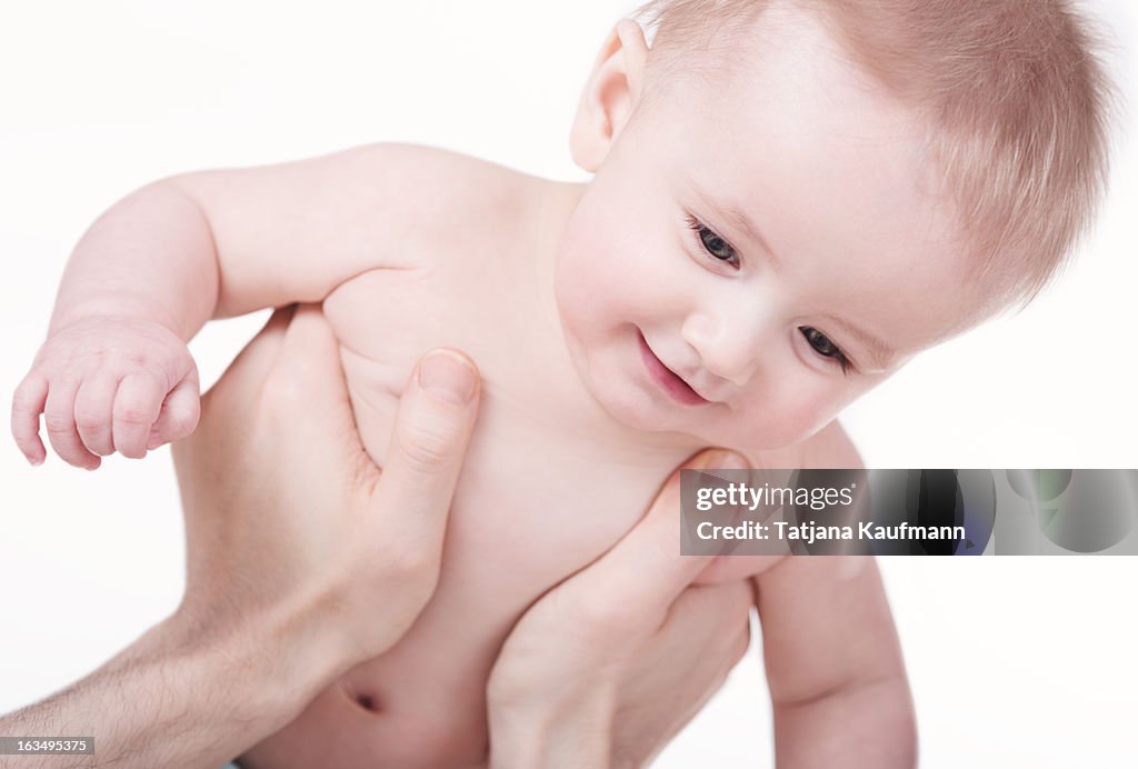 Smiling baby being lifted up by father