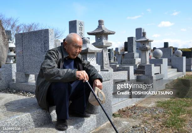 An elderly man sits as he and with his wife visit a cemetery to pay respects to their son who was killed in the March 2011 tsunami, in Minamisoma in...