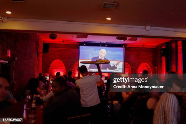 Republican presidential candidate and former U.S. Vice President Mike Pence is displayed on television screens at a watch party for the first 2024...