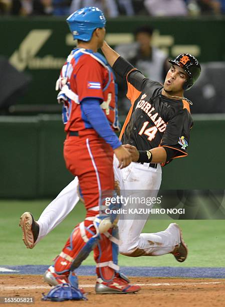 The Netherlands Randolph Oduber slides into home-plate as Cuba's catcher Frank Morejon looks on during the fourth inning of their second-round Pool 1...