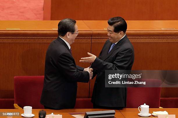 Newly-appointed Chairman of the Chinese People's Political Consultative Conference Yu Zhengsheng shakes hands with outgoing Chairman Jia Qinglin...
