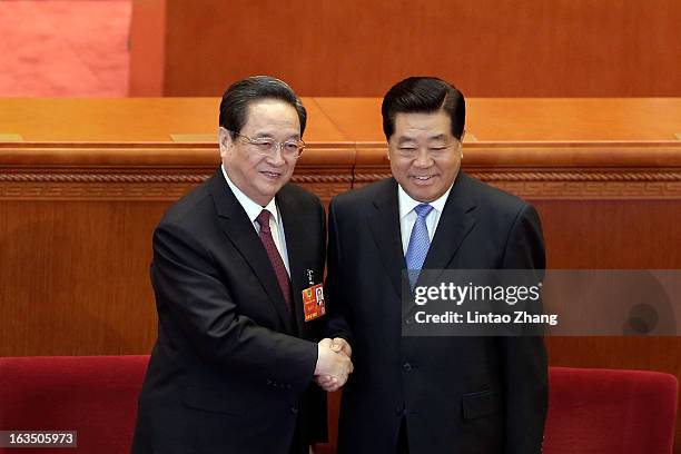 Newly-appointed Chairman of the Chinese People's Political Consultative Conference Yu Zhengsheng shakes hands with outgoing Chairman Jia Qinglin...