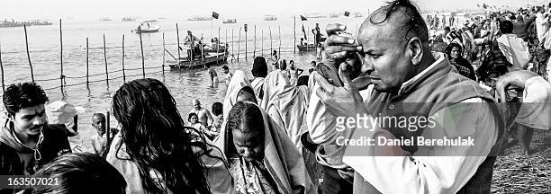 Hindu devotees dress themselves after having bathed on the banks of Sangam on January 13, 2013 in Allahabad, India. The Maha Kumbh Mela, believed to...