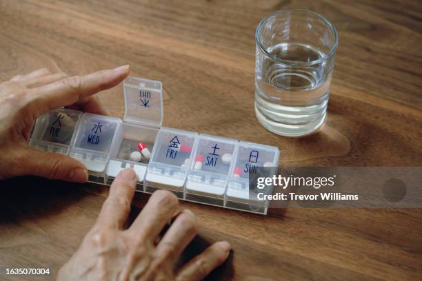 senior woman taking medicine from a weekly pill organizer - weekly stock pictures, royalty-free photos & images