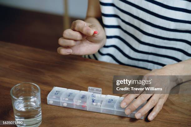 senior woman taking medicine from a weekly pill organizer - weekly stock pictures, royalty-free photos & images