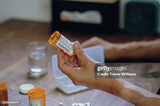 close-up of a male hand holding a pill bottle pouring medication into his hand - pill bottles stock pictures, royalty-free photos & images