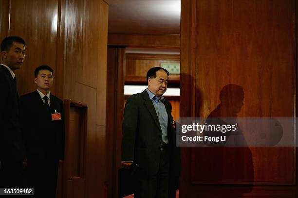 Delegate Mo Yan , the first Chinese national to win the Nobel Literature Prize, leaves the meeting room as the security personnel guarding during the...