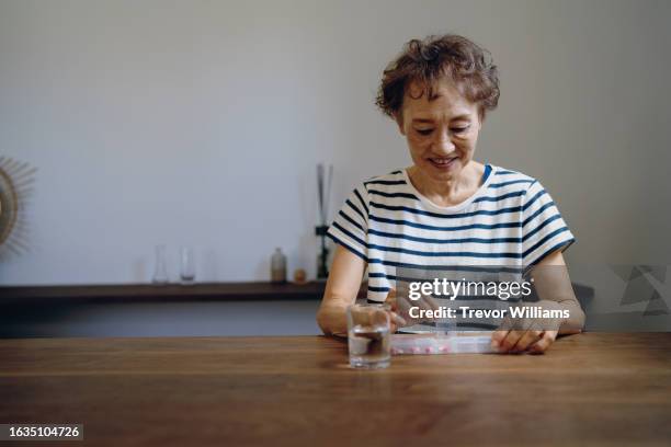 senior woman taking medicine from a weekly pill organizer - weekly stock pictures, royalty-free photos & images