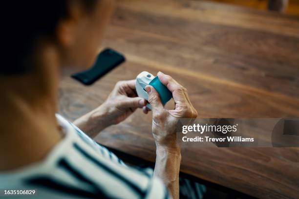 senior woman using an inhaler - asthmainhalator stock-fotos und bilder