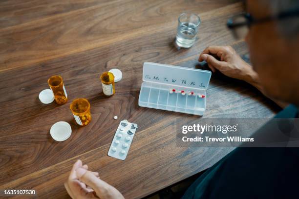 senior man taking various medications - enfermedad crónica fotografías e imágenes de stock