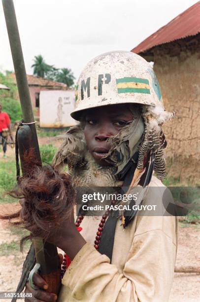 Rebel of the National Patriotic Front of Liberia wearing a helmet and a traditional outfit holds a rifle while patrolling 30 April 1990 in the border...