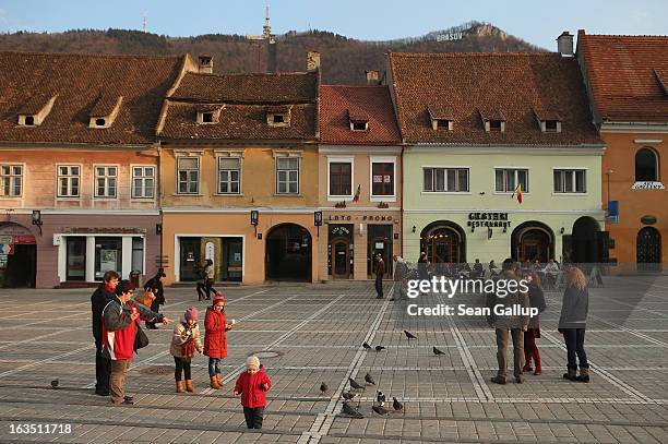 Weekend visitors relax in Sfatului square next to Saxon-built houses in the historic district on March 9, 2013 in Brasov, Romania. Brasov, in German...