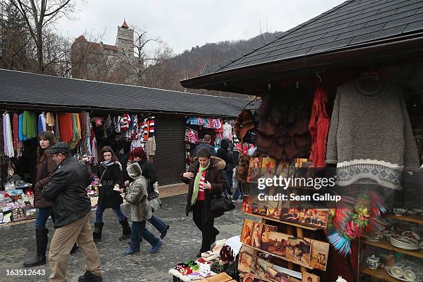 Visitors walk among souvenir shops backdropped by Bran Castle, famous as "Dracula's Castle," on March 10, 2013 in Bran, Romania. Bran Castle's...