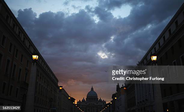 Night time falls over St Peter's Basilica as romans make their way home and catholic cardinals prepare to enter the conclave tomorrow and elect a new...