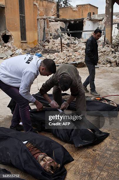 Syrian men search for their relatives amongst the bodies of civilians executed and dumped in the Quweiq river, in the grounds of the courtyard of the...