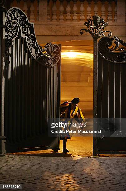 Member of The Swiss Guard closes the gate at the Arch of the Bells at St Peter's Basilica on March 11, 2013 in Vatican City, Vatican. Cardinals are...