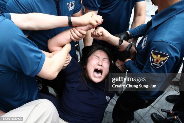 South Korean university student is detained by police officers on an attempt to break into the Japanese embassy on August 24, 2023 in Seoul, South...