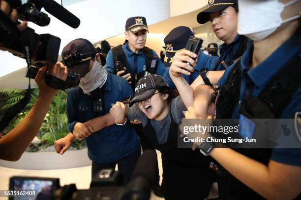 South Korean university student is detained by police officers on an attempt to break into the Japanese embassy on August 24, 2023 in Seoul, South...