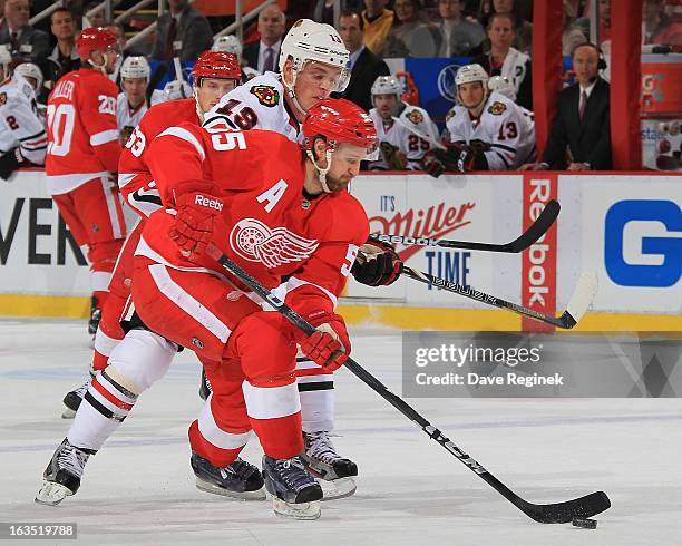 Niklas Kronwall of the Detroit Red Wings skates skates with the puck in front of Jonathan Toews of the Chicago Blackhawks at Joe Louis Arena on March...