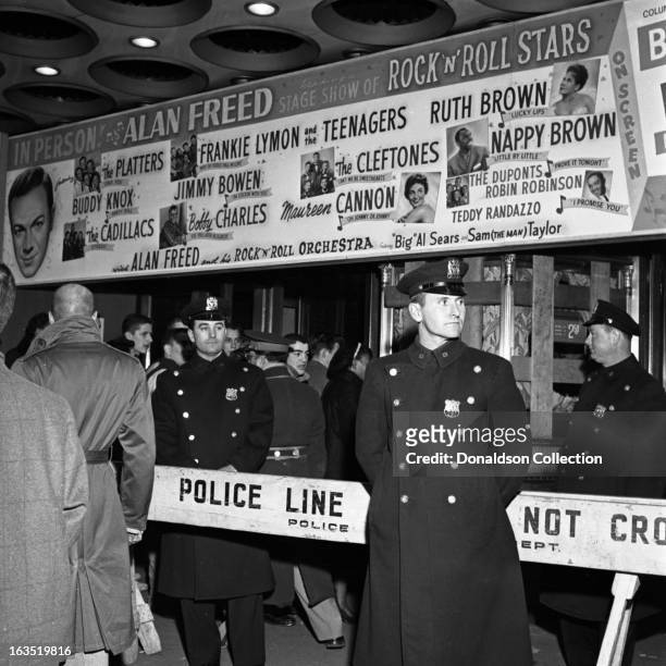 New York police officers stand around a gate that reads "Police Line Do Not Cross" in under the marquee that reads "In Person Alan Freed heading a...