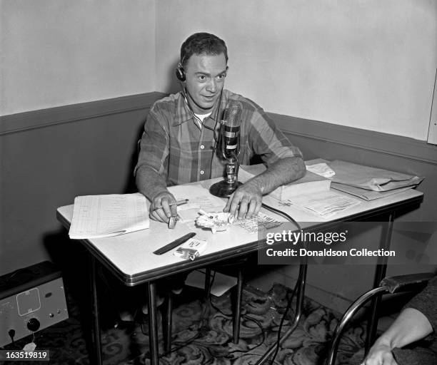 Disc jockey and promoter Alan Freed sits at a vintage microphone during a radio broadcast on September 6, 1955 in New York, New York.