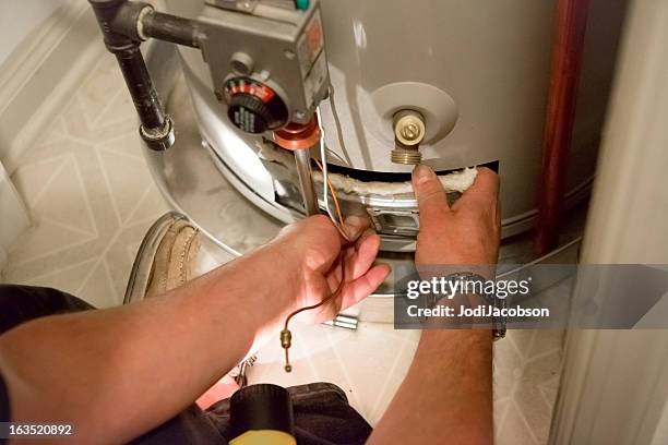 man shines flashlight on hot water heater - boilers stock pictures, royalty-free photos & images