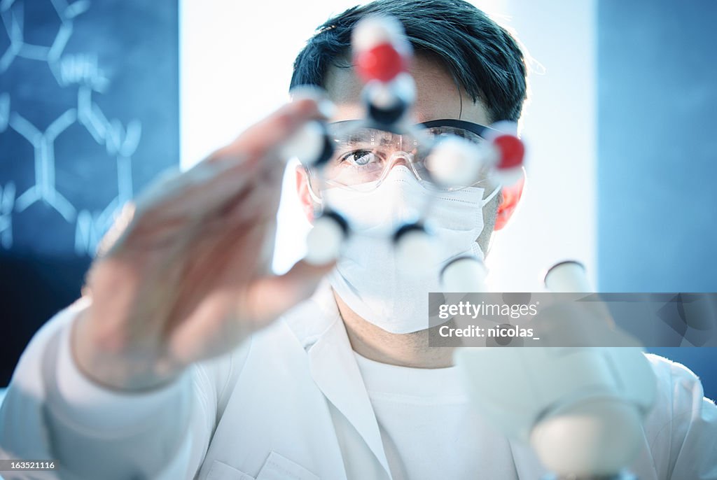 Scientist looking at the model of a molecule