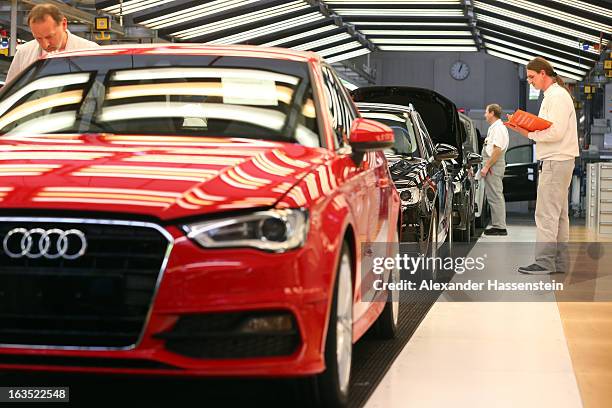An Audi employee carries out the final inspection on a row of Audi A3 automobiles, produced by Volkswagen AG's Audi brand, as they move along the...