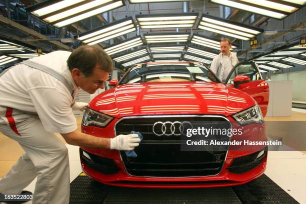 An Audi employee polishes the hood of an Audi A3 automobile, produced by Volkswagen AG's Audi brand, as it moves along the production line at the...