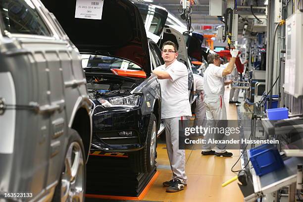 Audi employee work on the interior of an Audi A3 automobile, produced by Volkswagen AG's Audi brand, as the vehicle moves along the production line...