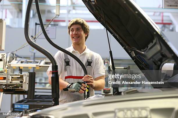 An Audi employee works on an engine for an Audi A3 automobile, produced by Volkswagen AG's Audi brand, as the unit moves along the engine production...