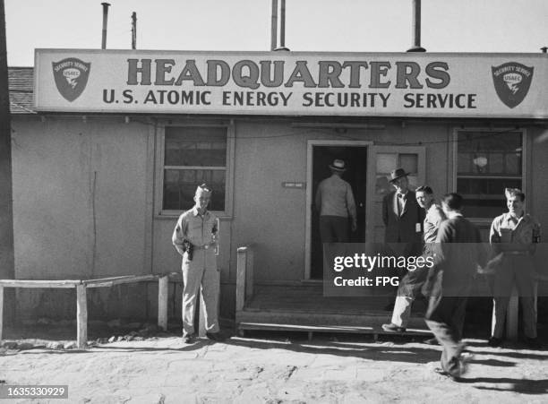 Group of men outside the entrance, which is guarded by Military Police, to the headquarters of the United States Atomic Energy Security Service at...