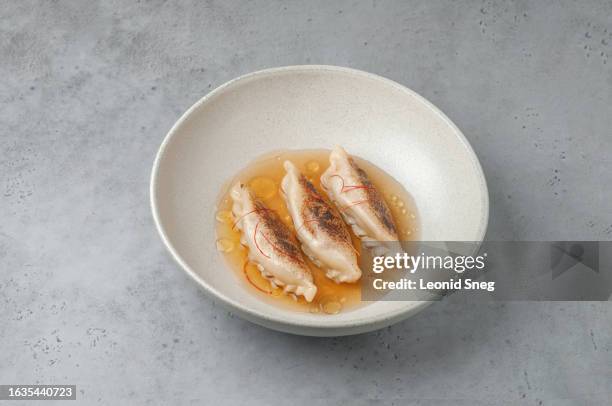 fried dumplings in spicy meat broth on gray background - chinese dumpling stock pictures, royalty-free photos & images