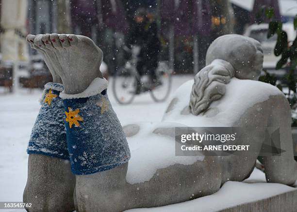 Sculpture of a naked woman is decorated with leg warmers as snow falls in Frankfurt am Main, western Germany, on March 12, 2013. Winter came back to...