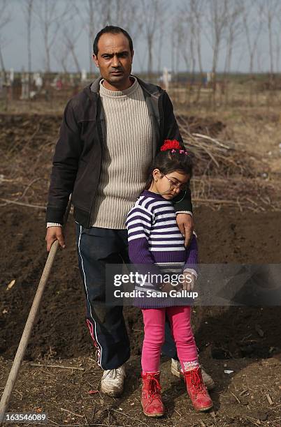 Marius Tanase, an ethnic Roma, and his daughter Denisa take a break while planting onions in their vegetable garden outside their home on March 11,...