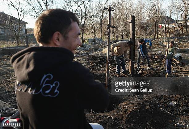 Ethnic Roma Marian Costea watches as his sons and a relative dig out iron columns that were part of a shed to make way for a vegetable garden on his...