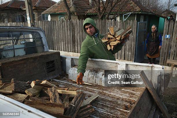 Ethnic Roma Serghei Percu delivers firewood to local elderly Roma resident Aurica Boboaca on March 11, 2013 in Dilga, Romania. Serghei and his...