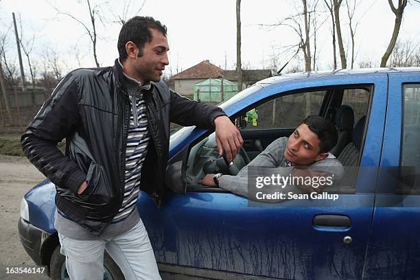 Vasile Nedelcu and his buddy Florin Arapu, both of them ethnic Roma, hang out at Vasile's car on March 11, 2013 in Dilga, Romania. Vasile's mother...
