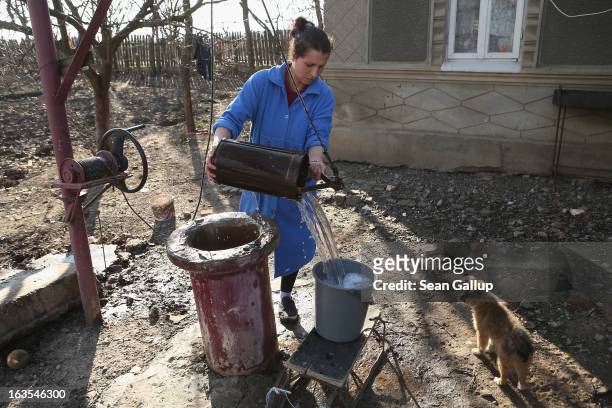 Ethnic Roma Mihaela Boboaca gets water from her well outside her home on March 11, 2013 in Dilga, Romania. Mihaela has worked as a migrant worker in...