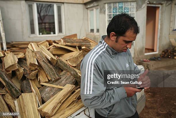 Ethnic Roma Victor Percu checks messages on his mobile phone before delivering firewood to a local family on March 11, 2013 in Dilga, Romania. Victor...