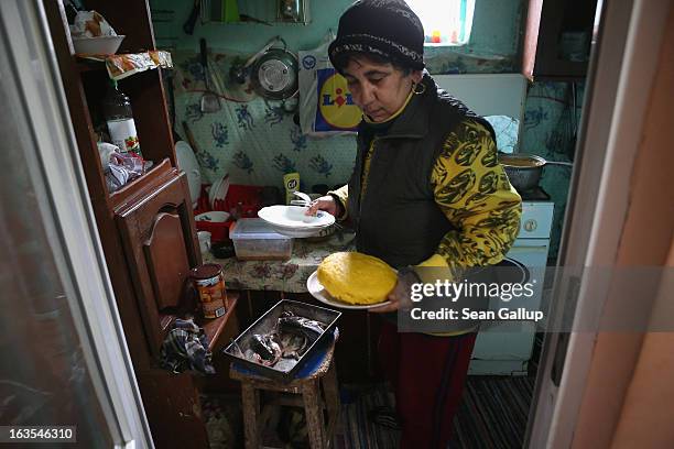 Aneta Enache, an ethnic Roma, prepares fried fish and mamaliga, a traditional Romanian dish made from cornmeal, at her home on March 11, 2013 in...