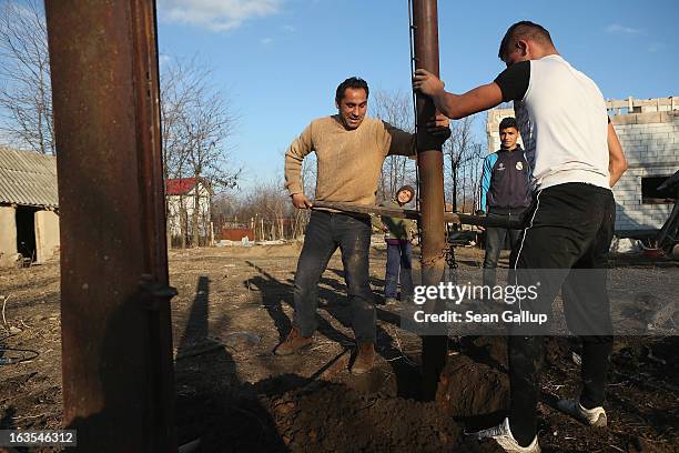 Ethnic Roma Ciprean Costea and his relative Costin Costea dig out iron columns that were part of a shed to make way for a vegetable garden on the...