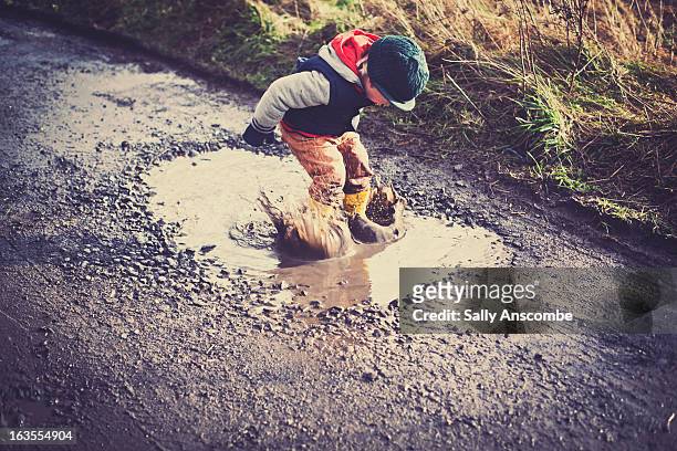 child jumping in a puddle - flaque photos et images de collection