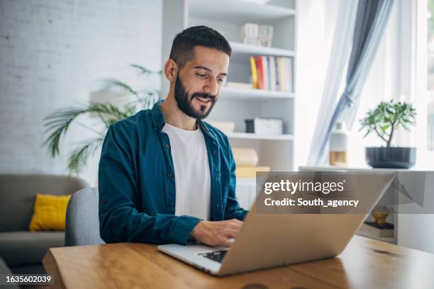 uomo che lavora su laptop a casa - lavori in casa foto e immagini stock