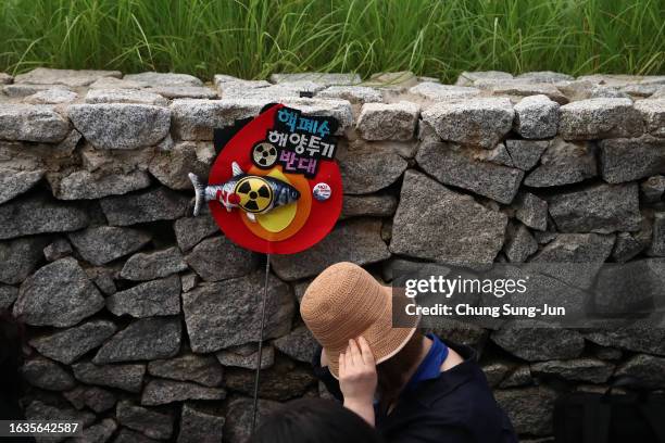 Woman participates in a rally against the release of treated radioactive water from the damaged Fukushima nuclear power plant into the Pacific Ocean,...