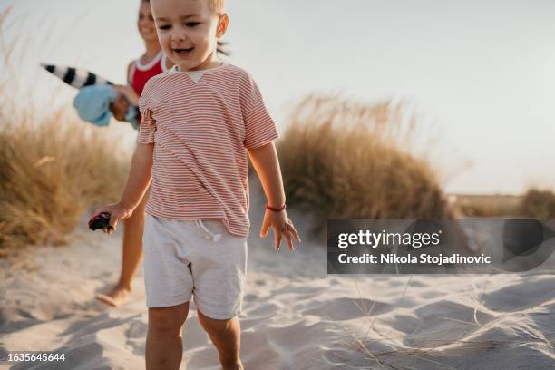 young mother and her toddler son playing tag on the beach - family playing tag stock pictures, royalty-free photos & images